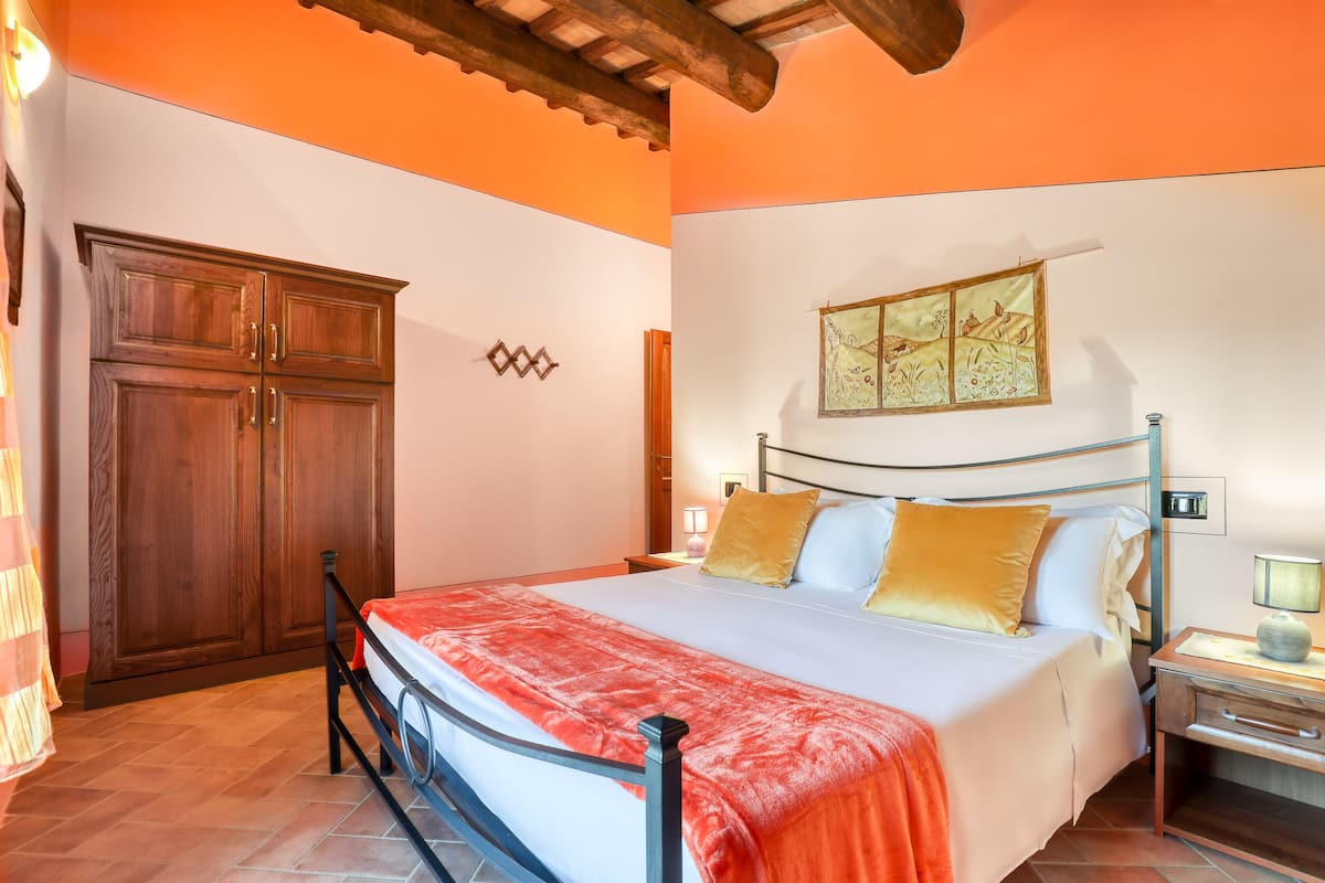 A bedroom with a bed, wooden wardrobe, and a wall-mounted artwork.