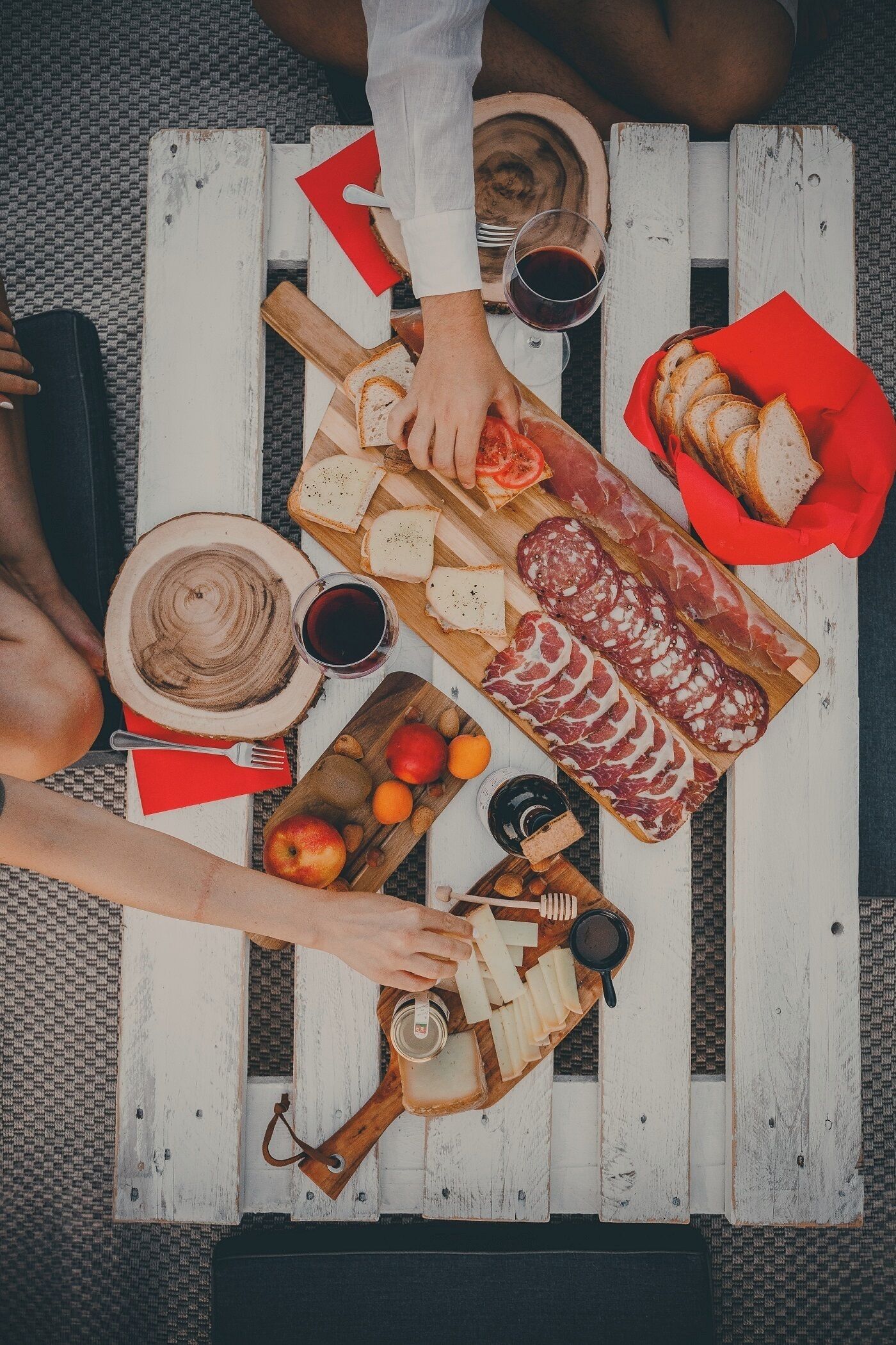 Un tavolo di legno con diversi cibi e bevande, tra cui pane, formaggio e un tagliere di salumi.