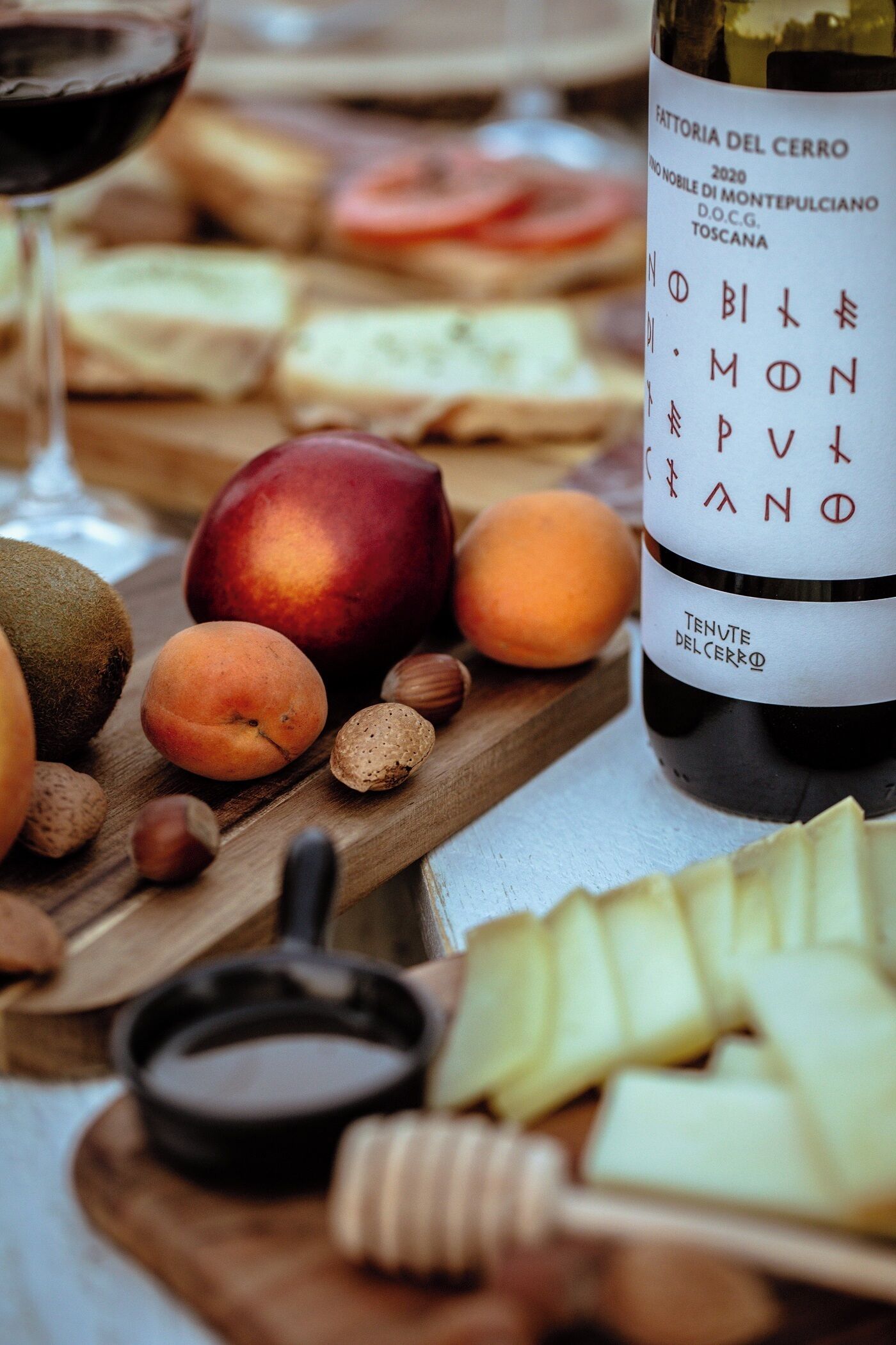 Una bottiglia di vino, frutta e formaggio su un tagliere di legno.