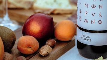 Una bottiglia di vino, frutta e formaggio su un tagliere di legno.