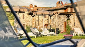 Un edificio de piedra con un patio que cuenta con sillones y sombrillas.
