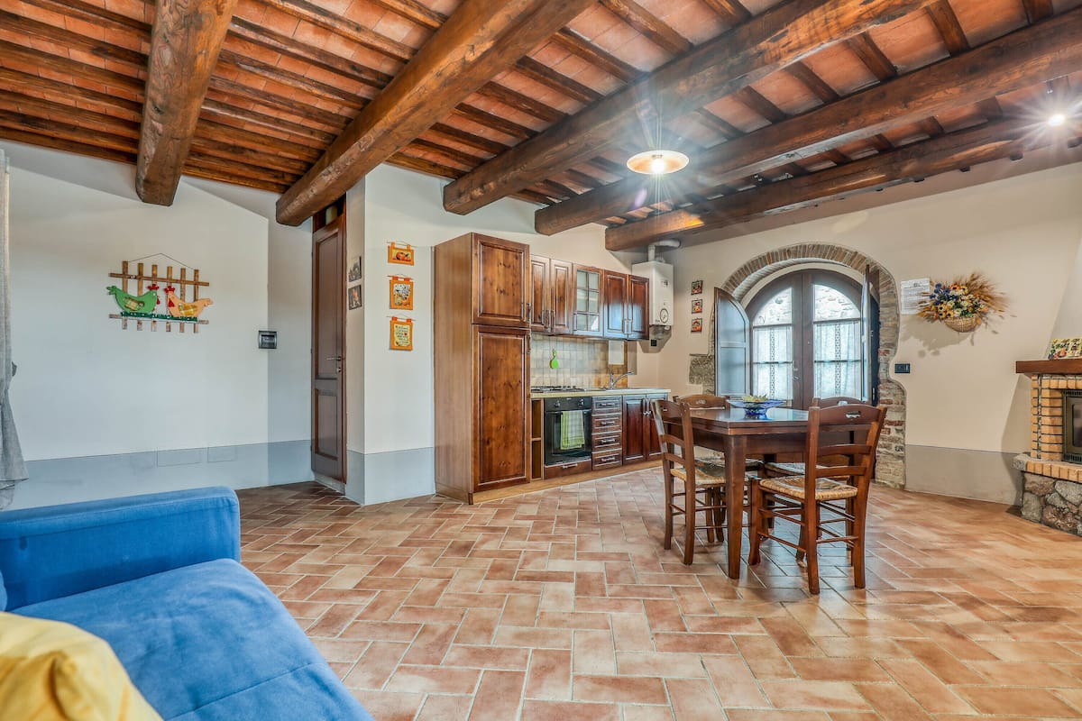 A rustic kitchen with wooden cabinets, a dining table, and a blue sofa.