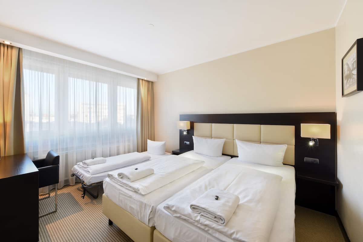 Ein Hotelzimmer mit zwei Betten, einem Schreibtisch und einem Stuhl.