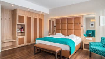 Una habitación de hotel moderna con una cama grande, un banco, un escritorio y un armario.