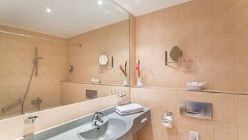Un baño moderno con un espejo grande, un lavabo de granito, un cabezal de ducha manual y un perchero para toallas.