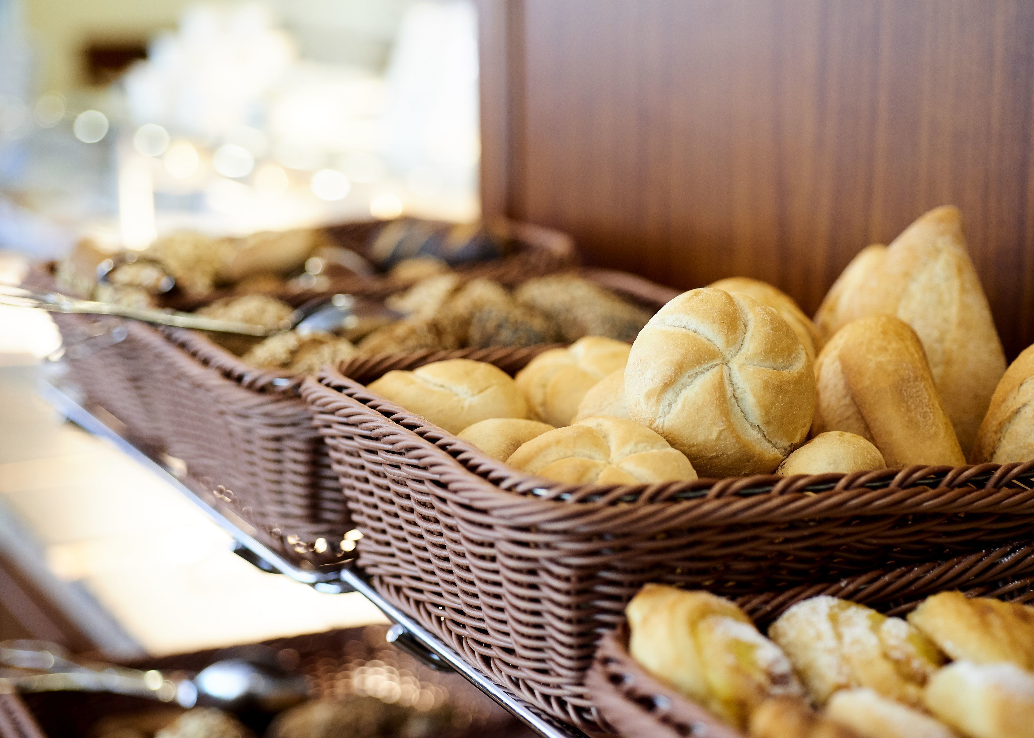 A buffet with various baked goods, including bread rolls and pastries, arranged in wicker baskets.