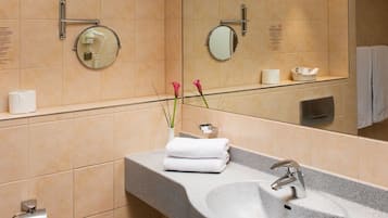 Un baño con lavamanos de granito, un espejo, un perchero para toallas y un dispensador de papel higiénico.