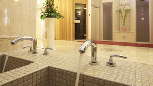 Un baño de hotel con dos lavamanos, una planta en maceta y una puerta de madera.