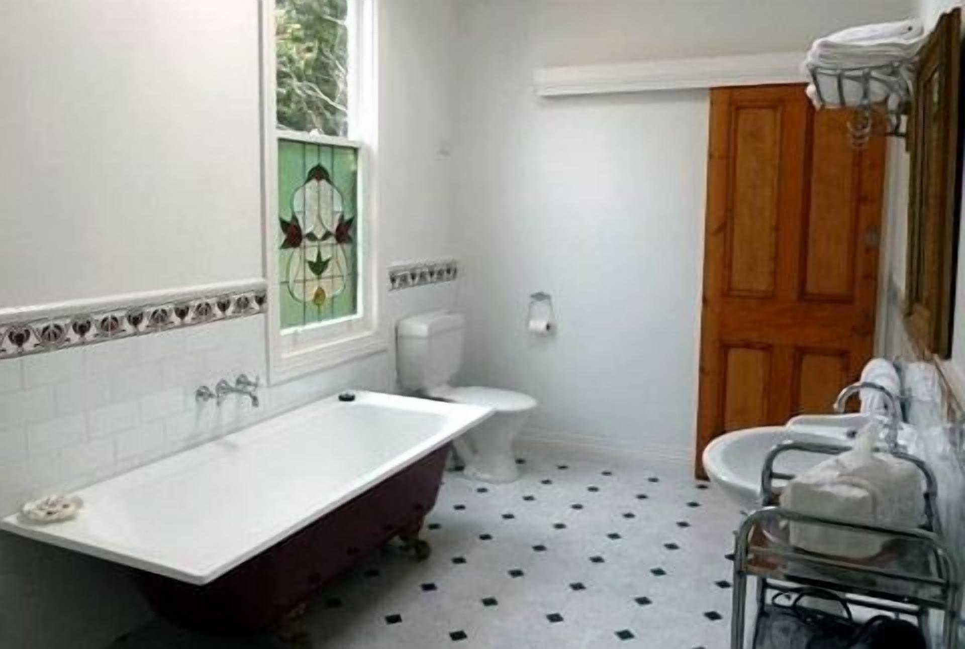 A bathroom with a clawfoot tub, a toilet, a sink, and a wooden door.
