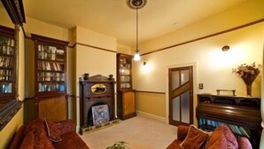 A cozy living room with a fireplace, bookshelves, and comfortable seating. - The Duck House (Burnie)
