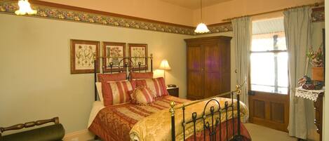 A traditional bedroom with a four-poster bed, a wooden wardrobe, and a window with curtains.