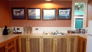 A kitchen with wooden cabinets, a sink, and framed pictures on the wall. - The Duck House (Burnie)
