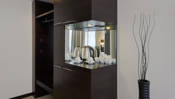 A modern kitchen with dark cabinetry, a built-in stove, and a vase with branches. - Zi Hotel & Lounge (Karlsruhe)