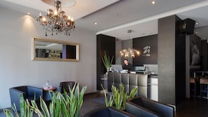A modern hotel lobby with a reception desk, seating area, and a chandelier. - Zi Hotel & Lounge (Karlsruhe)