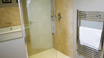 A glass-enclosed shower with a white towel on a metal rack.