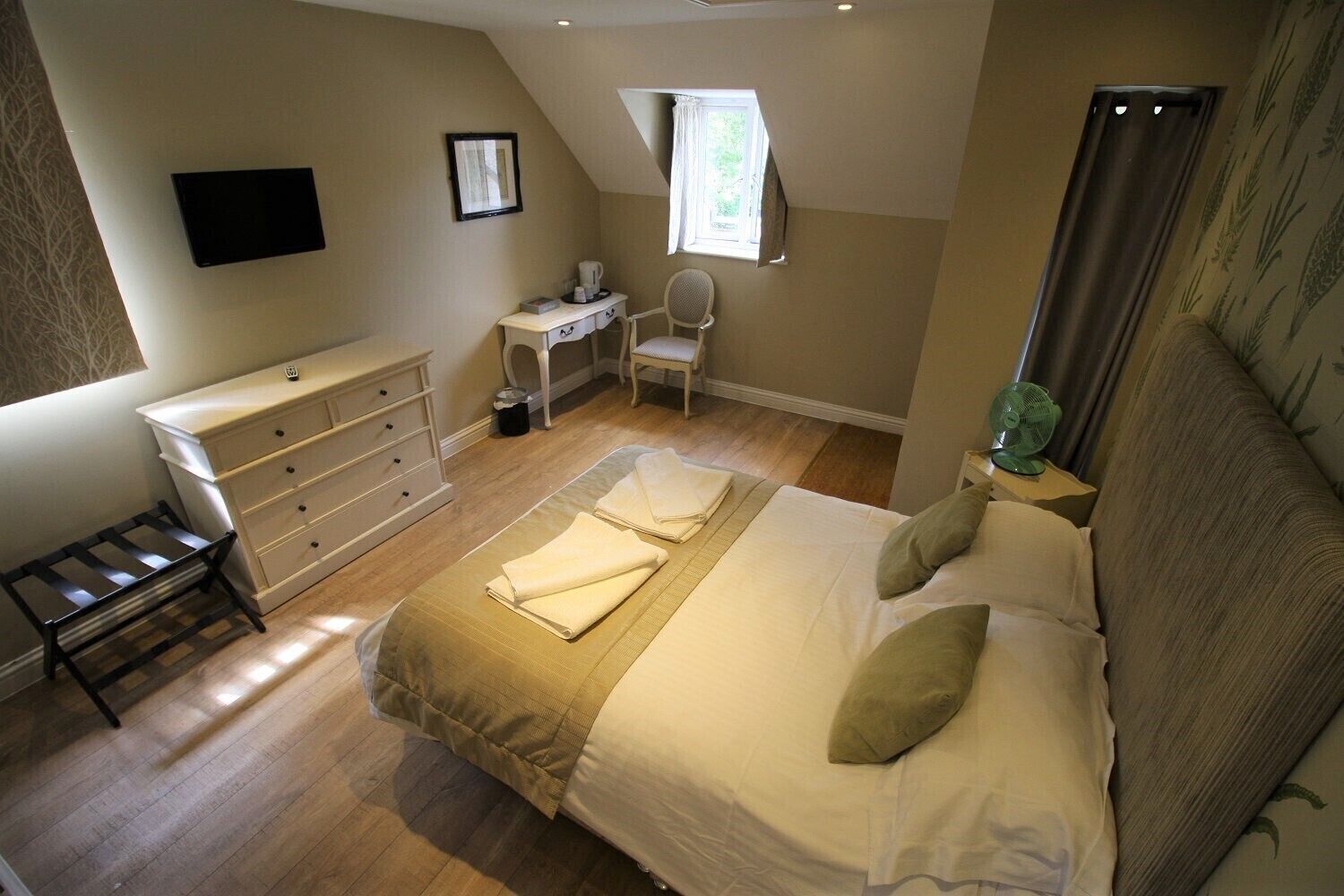 A bedroom with a bed, a desk, a chair, and a small table.