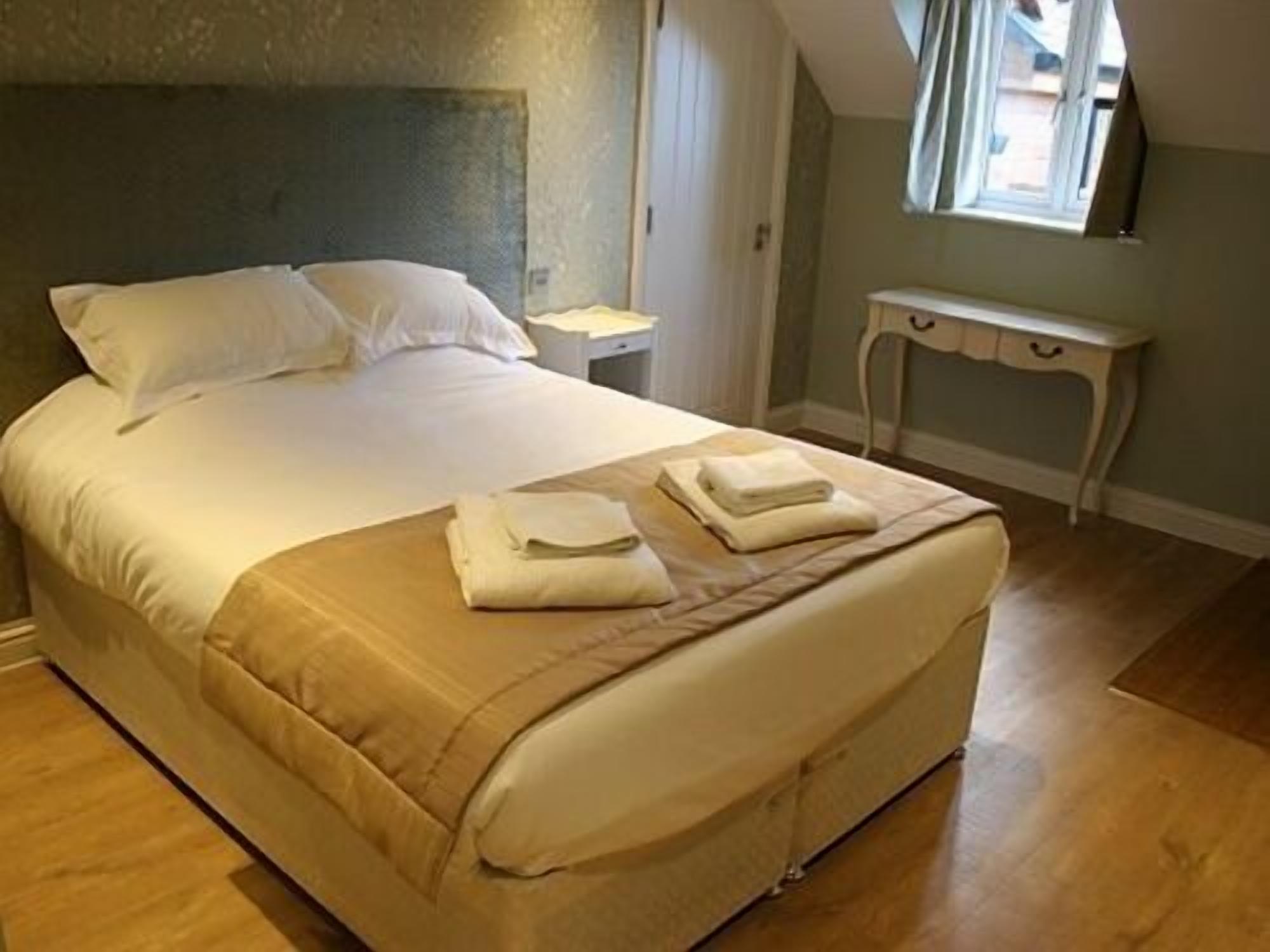 A neatly made bed with a headboard, a bedside table, and a small console table.
