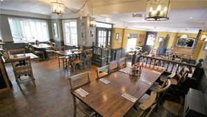 A restaurant with wooden tables and chairs, a bar area, and a view of the street. - The Sun Inn (Swindon)