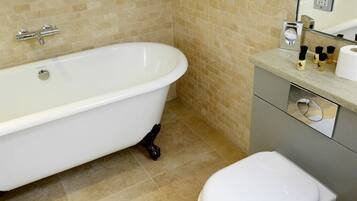 Un baño con una bañera blanca, un inodoro y un lavabo con artículos de aseo.