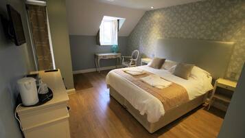 A neatly arranged bedroom with a bed, bedside table, and a desk with a chair.