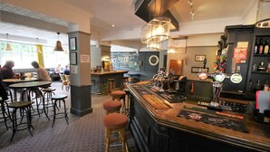 A bar area with stools, a bar counter, and a dartboard. - The Sun Inn (Swindon)