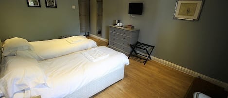 A bedroom with two beds, a dresser, a TV, and framed pictures on the wall.