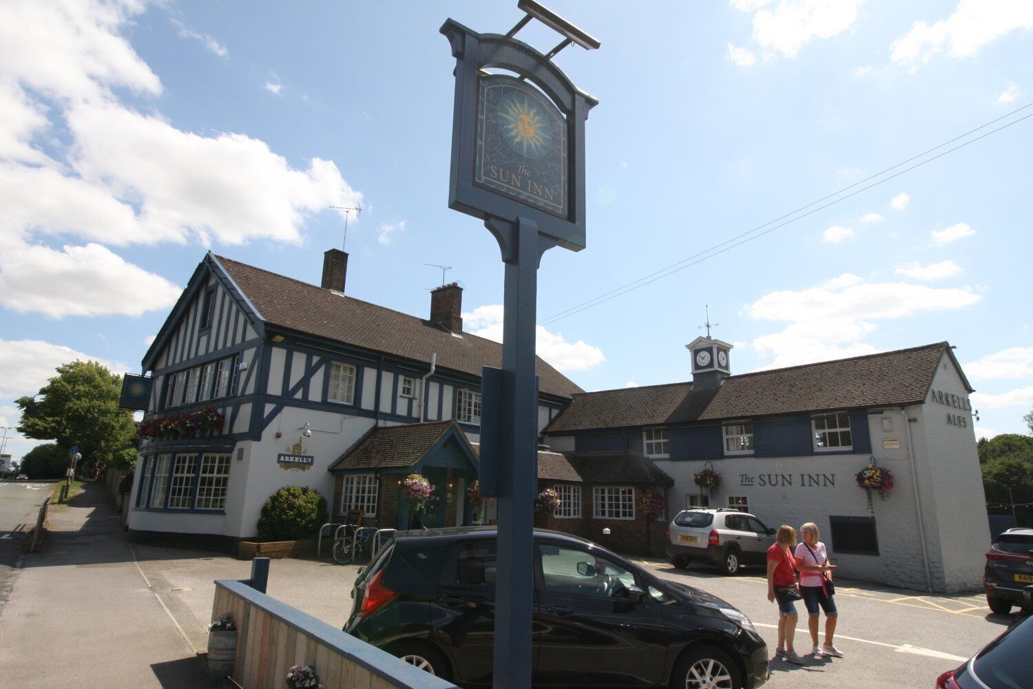 A traditional Tudor-style building with a sign for 'The Sun Inn' and 'Arkell's Ales' on the side.