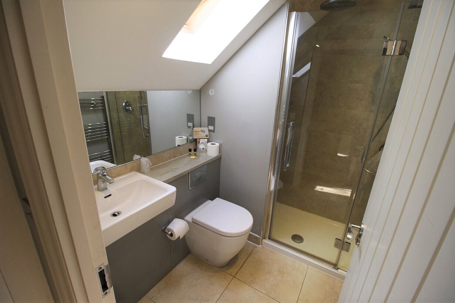 A modern bathroom with a glass-enclosed shower, a sink, and a toilet.