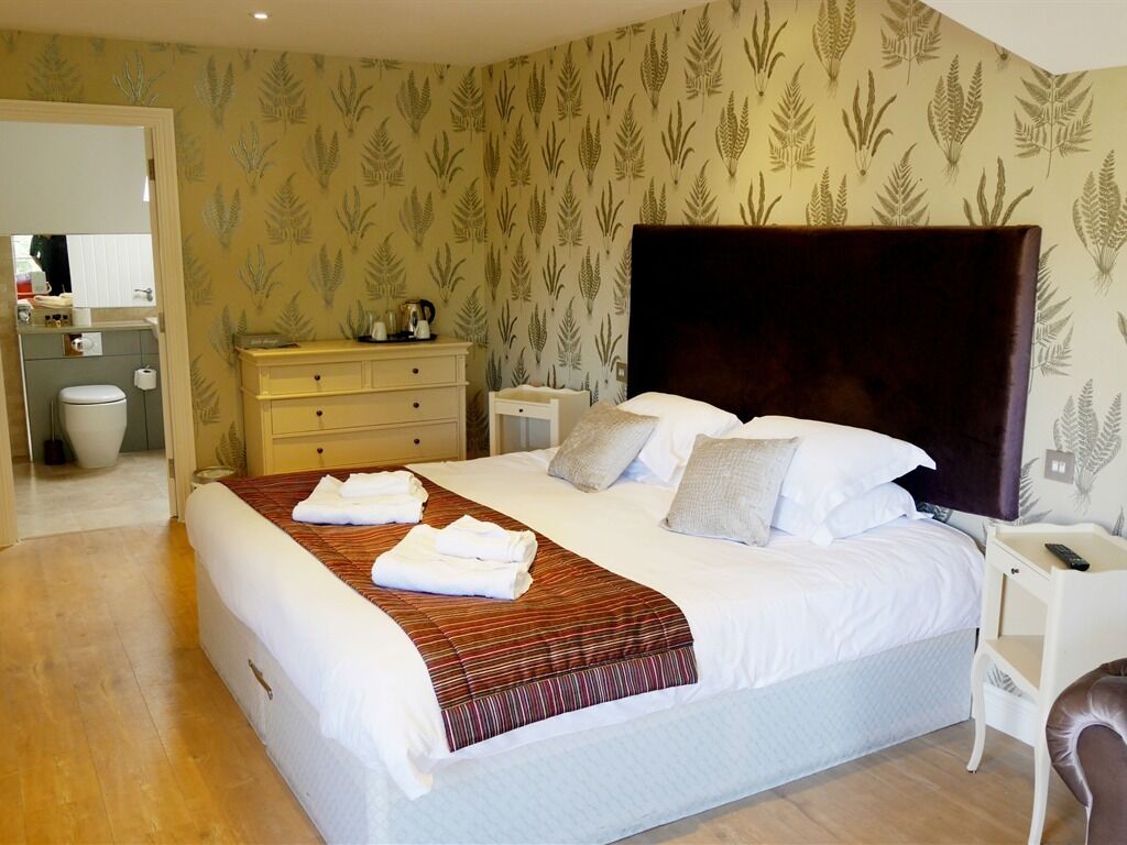 A hotel room with a large bed, a nightstand, a dresser, and a bathroom visible through an open door.