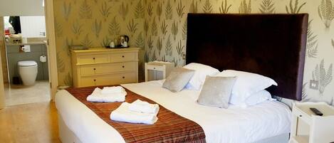 A hotel room with a large bed, a nightstand, a dresser, and a bathroom visible through an open door.
