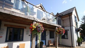 A two-story building with a balcony, outdoor seating, and hanging flower baskets. - The Sun Inn (Swindon)