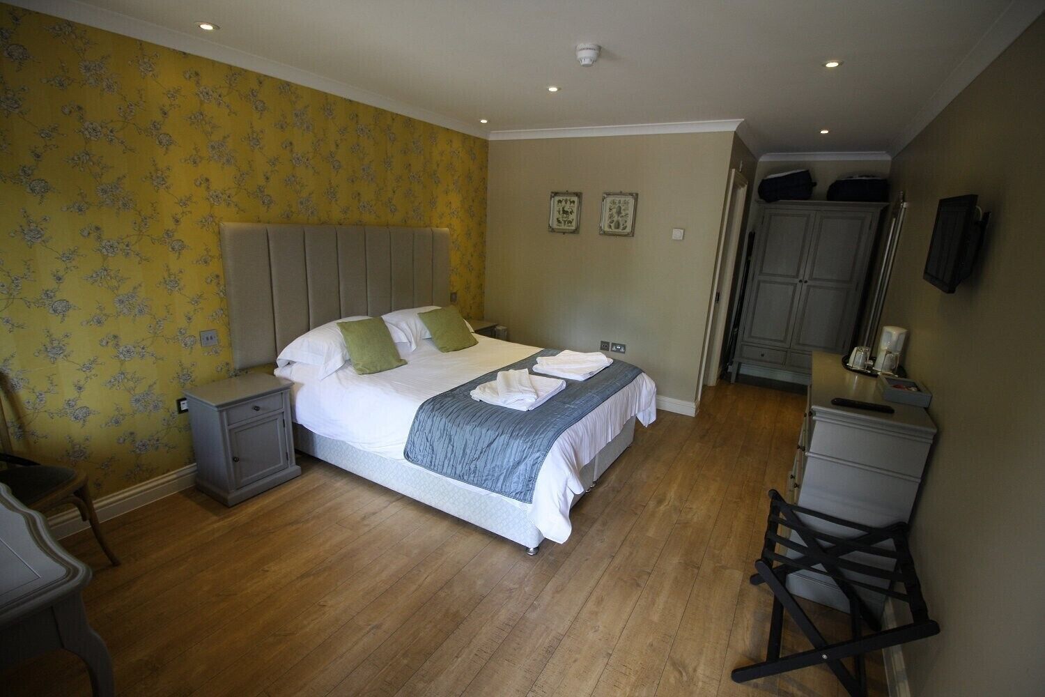 Un dormitorio con cama, mesitas de noche, cómoda y una silla.