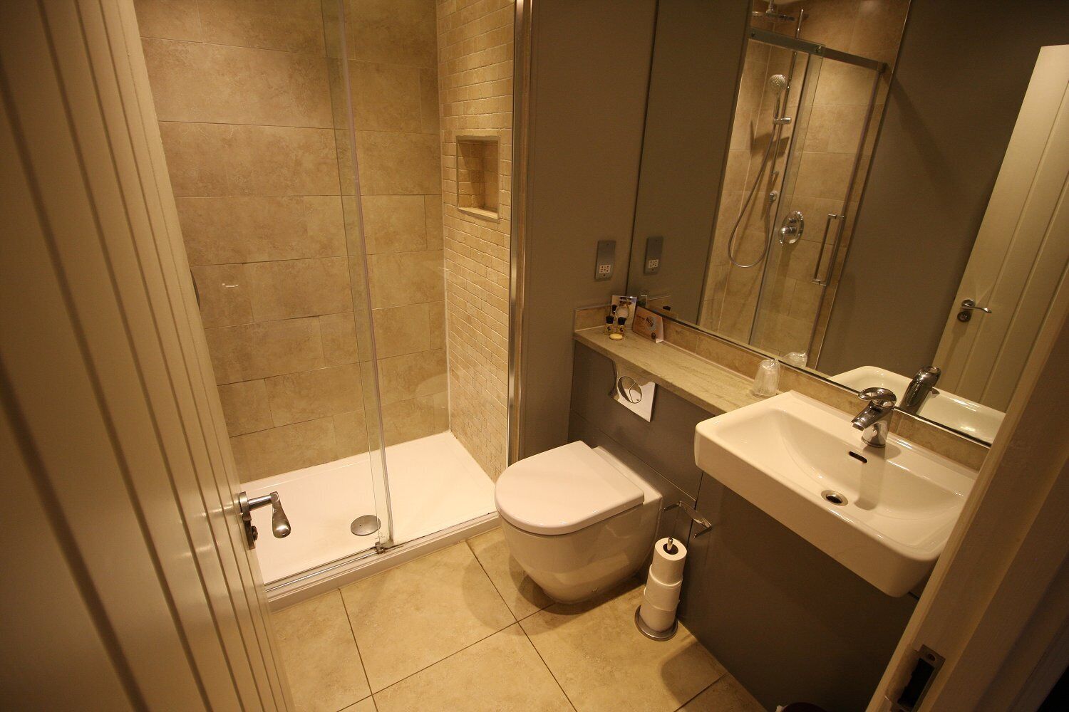 A modern bathroom with a glass-enclosed shower, a toilet, and a sink with a mirror above it.