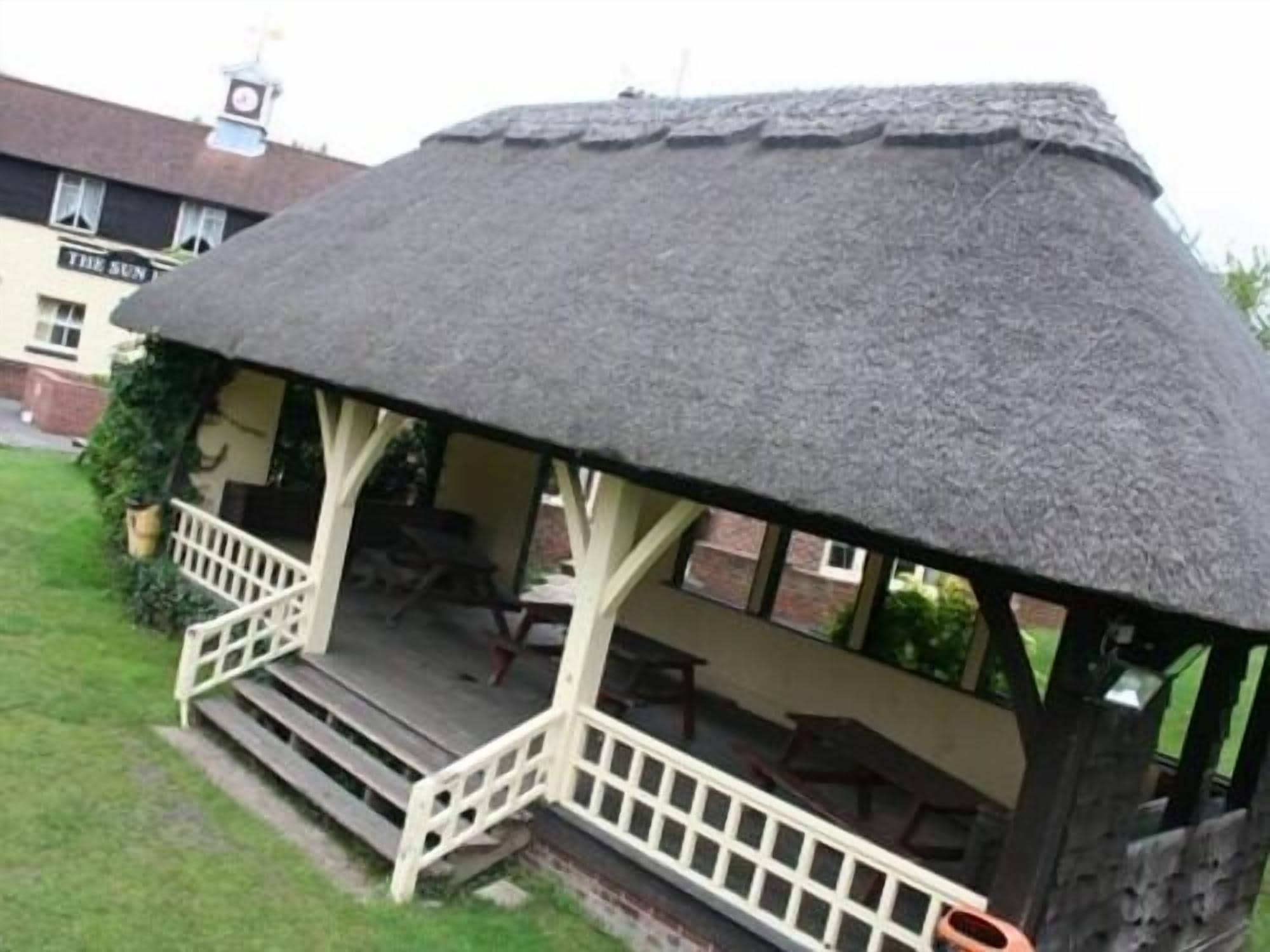 A thatched-roof structure with a white railing and steps leading up to it.