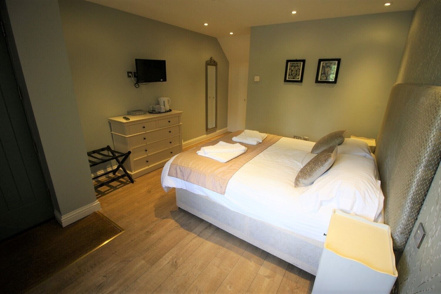 A bedroom with a bed, dresser, and a television on the wall.