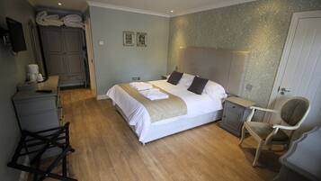 A bedroom with a bed, a chair, a desk, and a wardrobe.