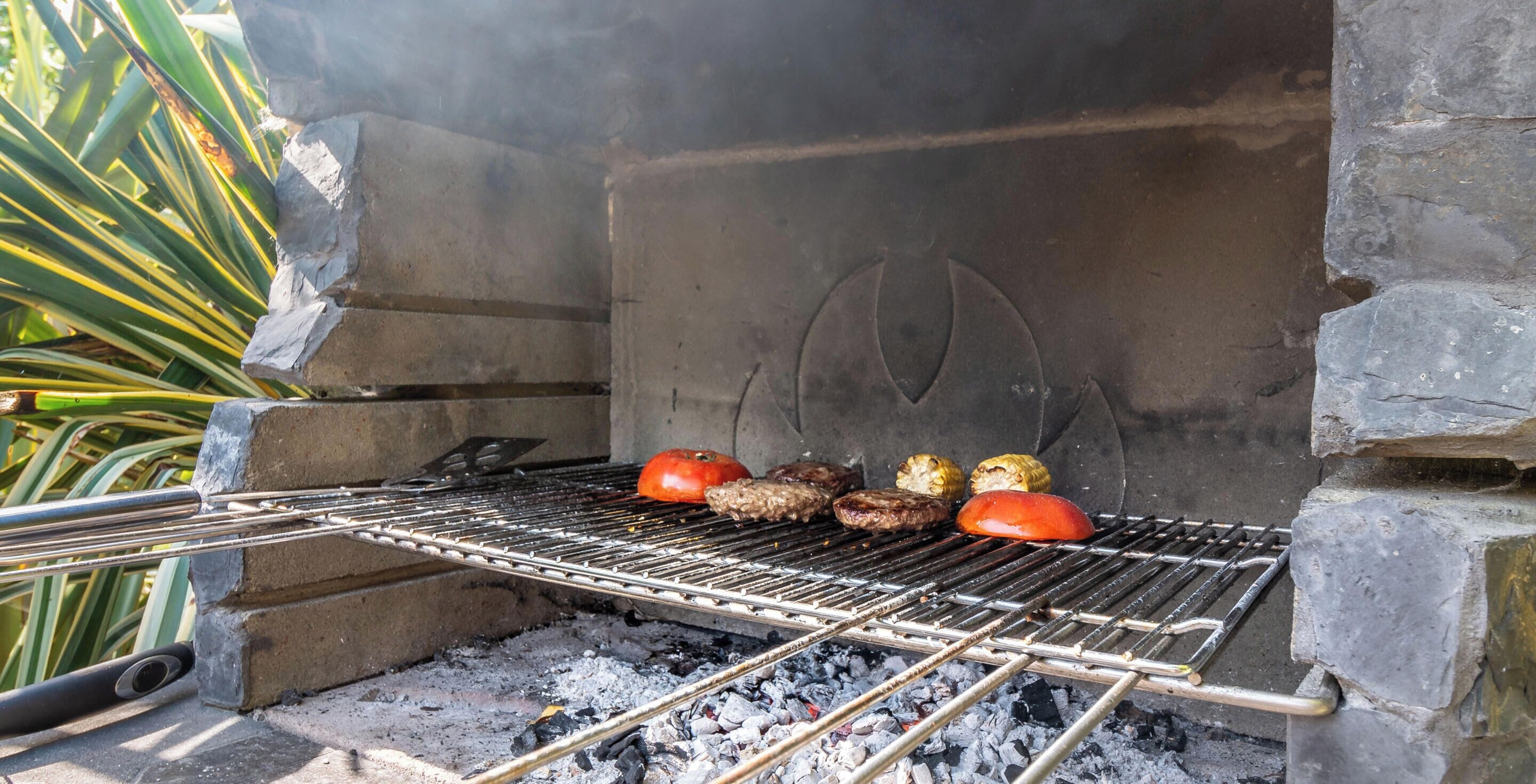 A charcoal grill with meat and vegetables being cooked.