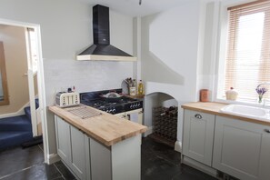 A kitchen with a central island, a stove, and a wine rack. - Withy Cottages (Langport)