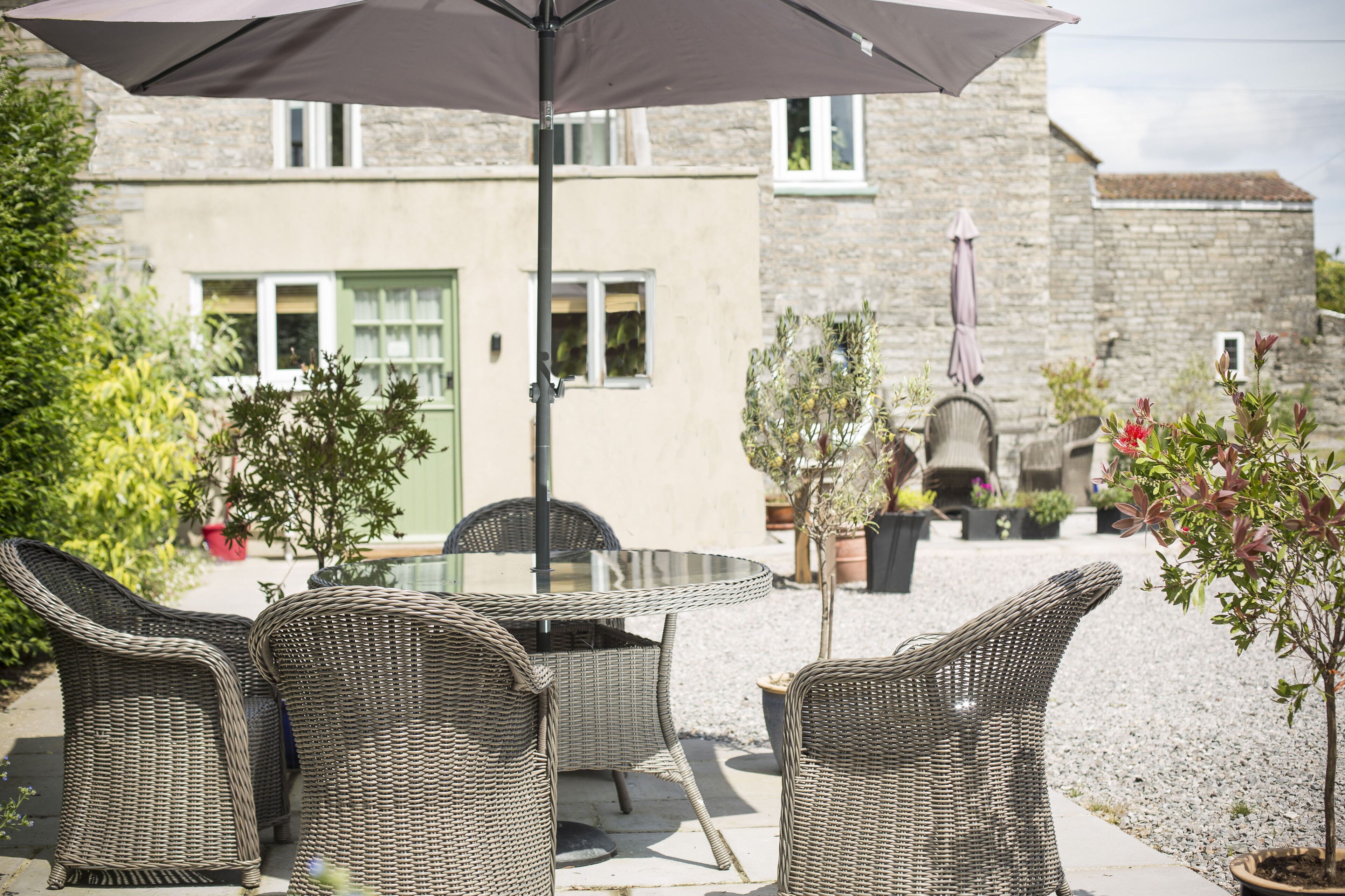 An outdoor patio with wicker furniture, a table, and an umbrella.