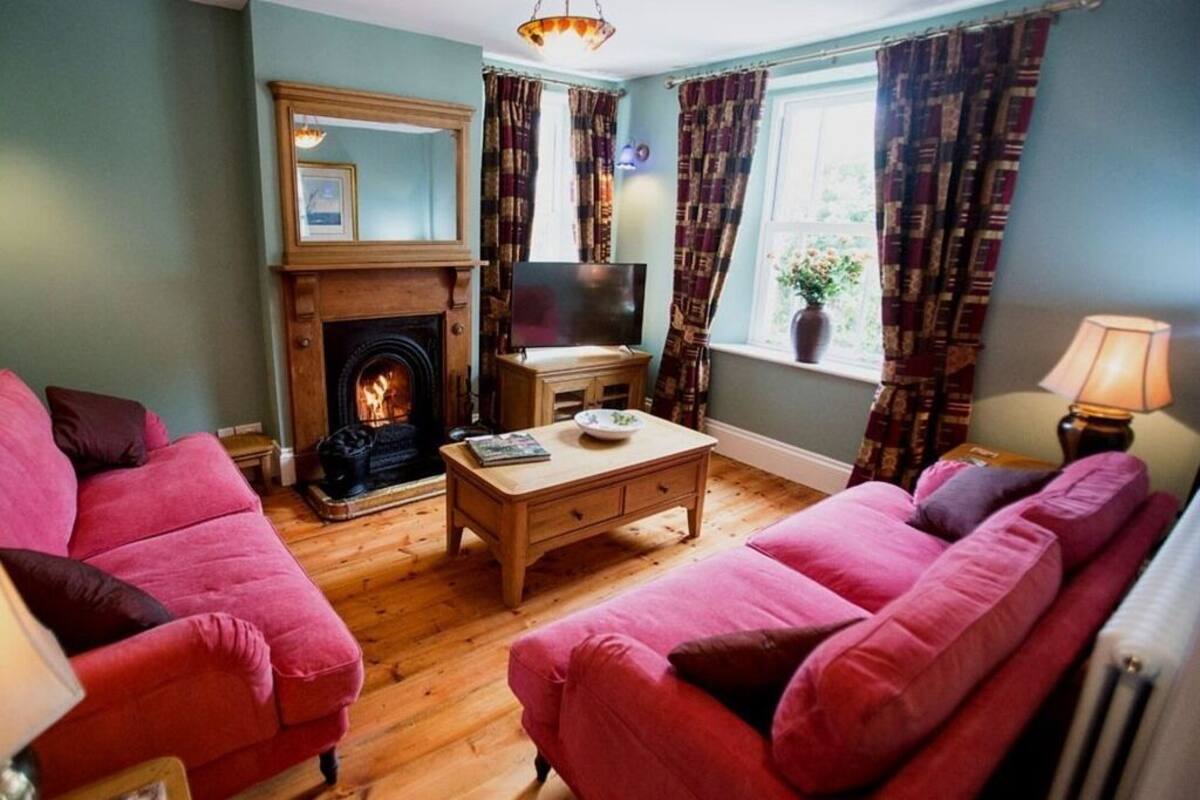 A cozy living room with a fireplace, two sofas, a coffee table, and a TV.