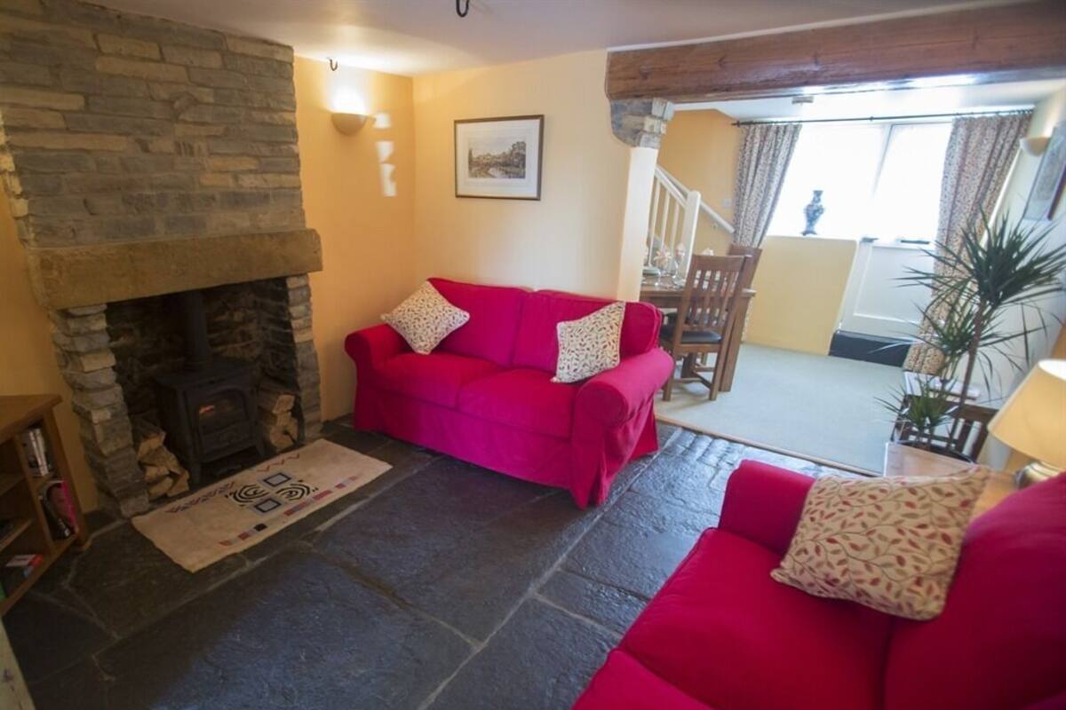 A cozy living room with a stone fireplace, a bright red sofa, and a dining area with a table and chairs.