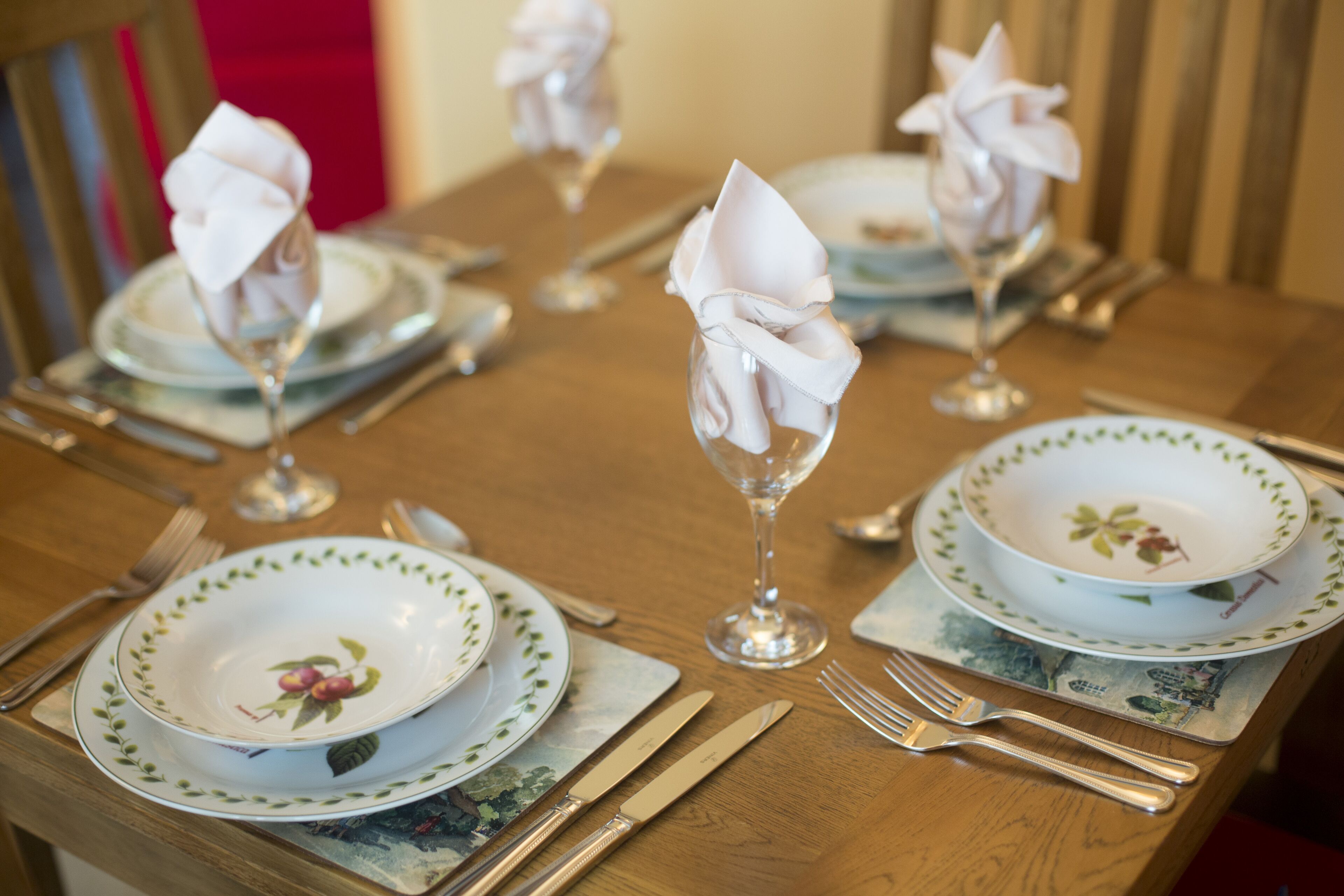 Une table à manger dressée avec des assiettes, des couverts et des serviettes.