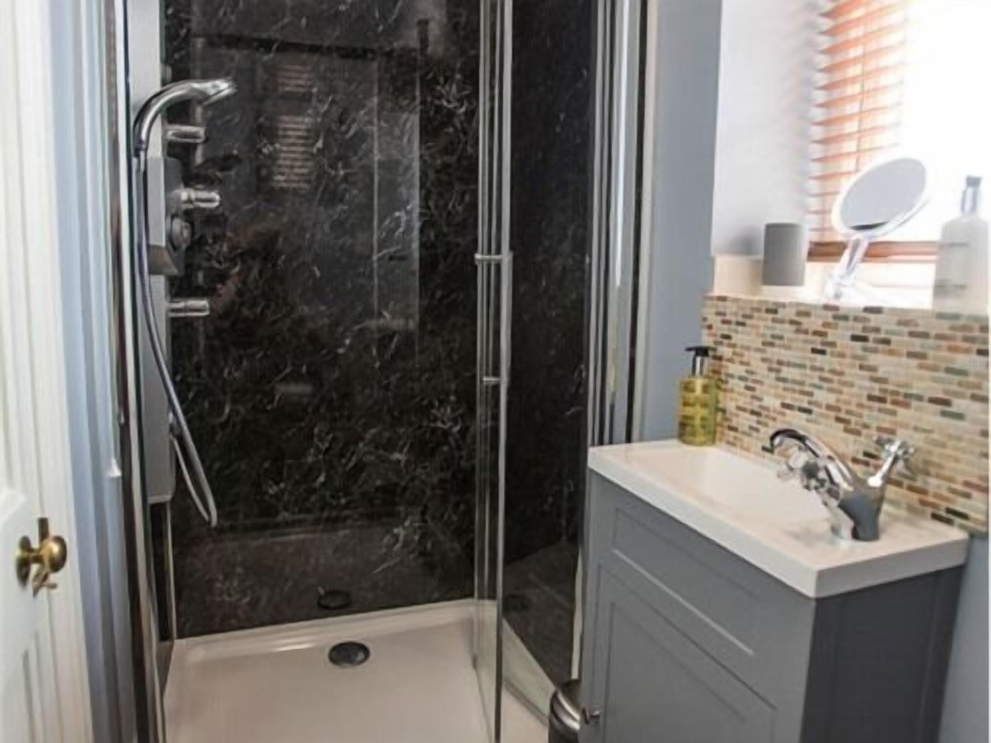 A bathroom with a glass-enclosed shower, a white sink, and a mirror above it.
