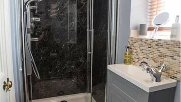 A bathroom with a glass-enclosed shower, a white sink, and a mirror above it.
