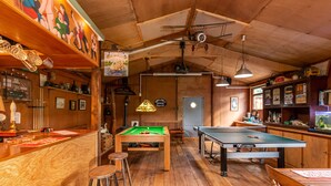 Una sala de billar con mesa de billar, taburetes y un acuario.