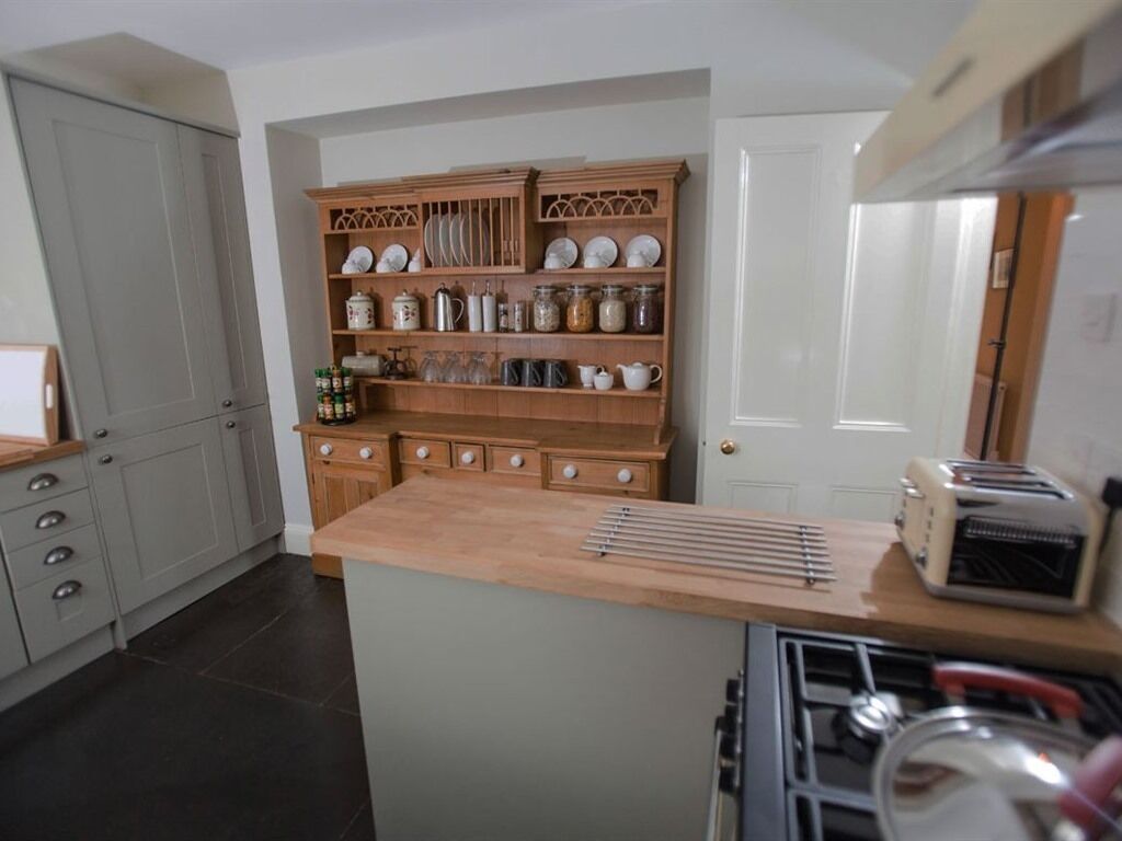 A kitchen with a central island, wooden cabinets, and a variety of kitchenware.