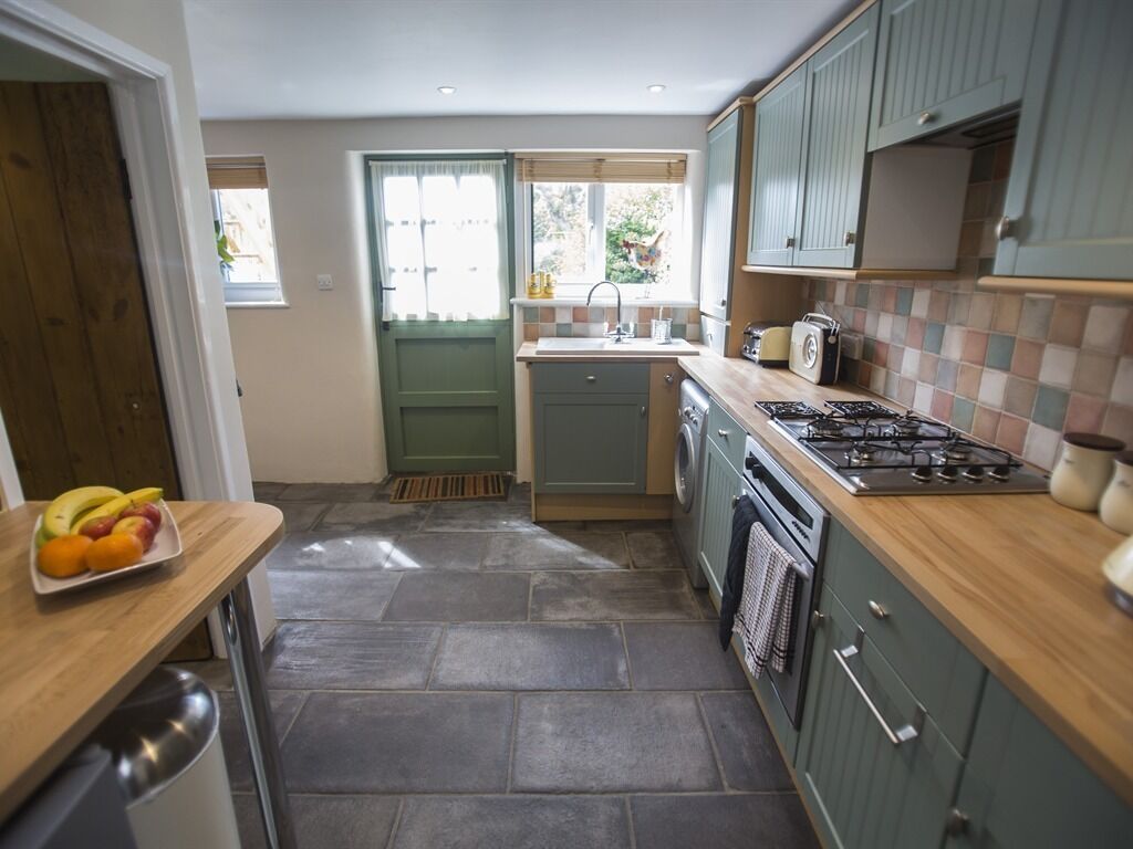 A compact kitchen with a wooden countertop, a gas stove, a washing machine, and a sink.
