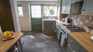 A compact kitchen with a wooden countertop, a gas stove, a washing machine, and a sink.