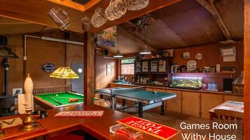 A games room with pool tables, a dartboard, and a fish tank.