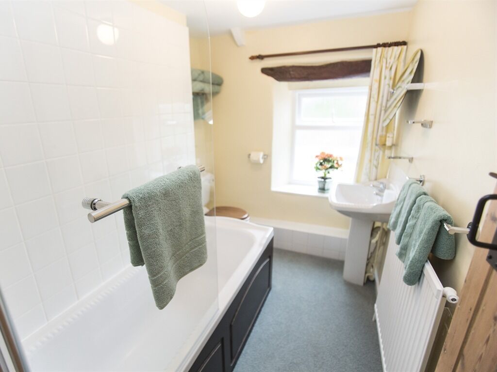 A bathroom with a bathtub, a sink, and a window with curtains.